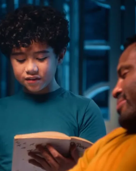 Pai e filho folheando um livro juntos enquanto esperam o pedido